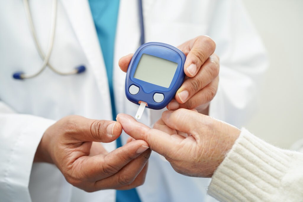 doctor using digital glucose meter for check sample blood sugar level to treatment diabetes