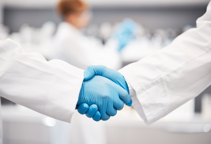 Doctor, shaking hands and gloves for safety in healthcare, partnership or trust for collaboration, unity or support at lab. Team of medical experts handshake in teamwork for agreement or success Two lab scientists shaking hands in gloves